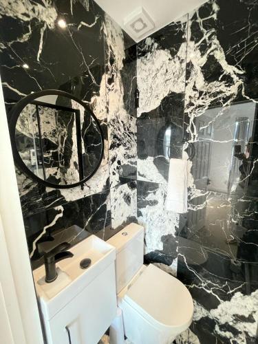 a bathroom with a black and white marble wall at Stone Lodge 2 min Walk From Edgware Underground in Edgware
