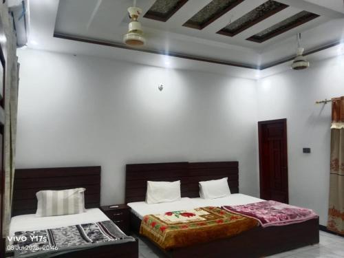 two beds in a room with white walls at Bijarani Guest House in Mīrpur Khās