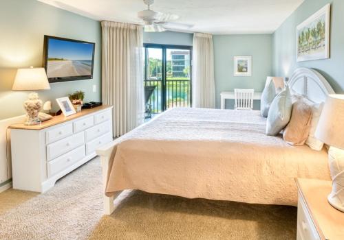 a bedroom with a large bed and a balcony at Pointe Santo D27 condo in Sanibel