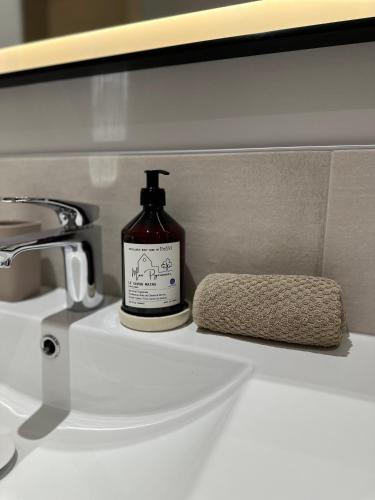 - une bouteille de savon assise au-dessus d'un lavabo dans l'établissement Ancien Pigeonnier Centre-Ville historique de Vesoul Bain nordique Terrasse Jardin Animaux bienvenus, à Vesoul
