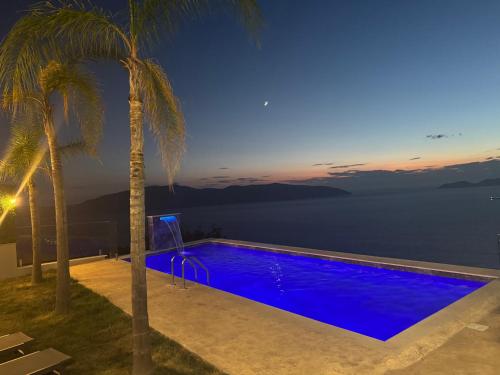 a swimming pool with a view of the ocean at night at Villa e Diellit in Kaninë