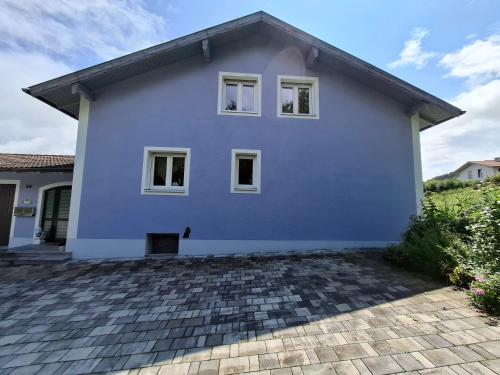 a blue house with white windows and a brick driveway at Haus Seeglück in Taching am See