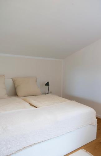 a white bed with white sheets and a lamp at Ferienhaus Fringaluna in Übersee