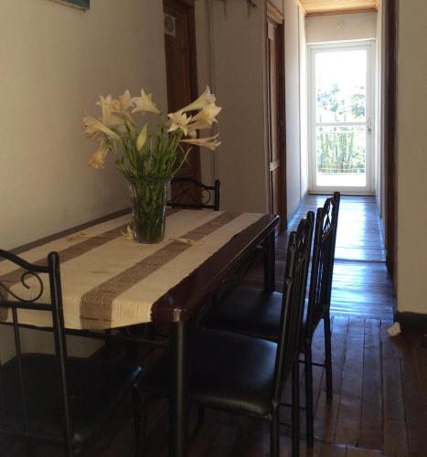 ein Esstisch mit einer Vase mit Blumen darauf in der Unterkunft TANA-JACARANDA in Antananarivo