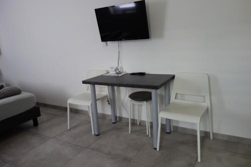 a black table with chairs and a television on a wall at Apartmán HARMONY - Lipno nad Vltavou in Lipno nad Vltavou