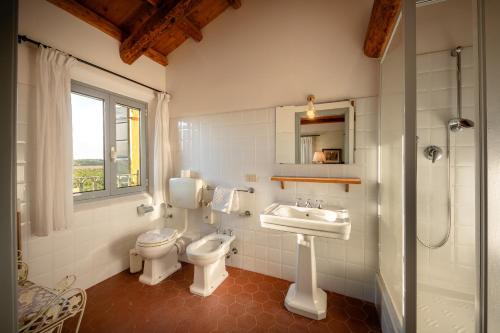 a white bathroom with a toilet and a sink at Agriturismo Lemene in Caorle