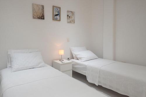 two white beds in a white room with a lamp at edificio Alba in Cartagena de Indias