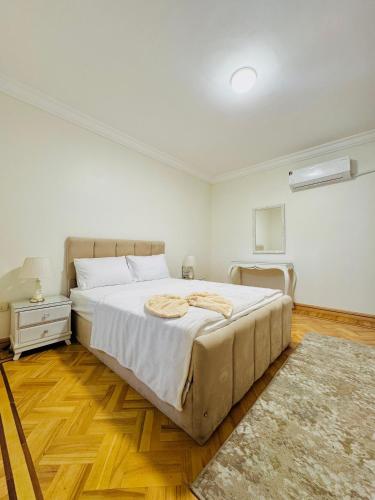 a white bedroom with a large bed and a night stand at ALEX HOMES - Gleem Luxury Apartments with Direct Sea View in Alexandria