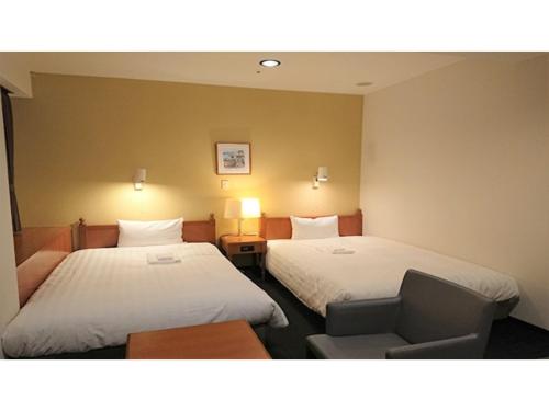 a hotel room with two beds and a chair at Smile Hotel Kobe Motomachi - Vacation STAY 85865v in Kobe