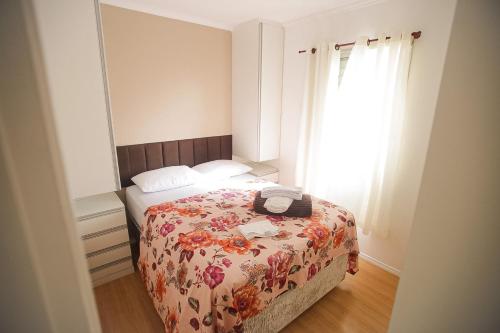 a bedroom with a bed with a floral bedspread and a window at Apt Confortável Cent de SP Luz Brás e Bom Retiro in Sao Paulo