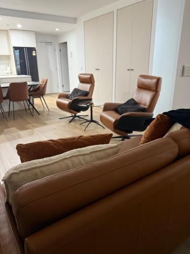 a living room with a couch and chairs at Modern Minimalist Apartment in Belconnen
