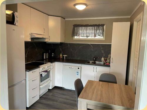 a kitchen with white appliances and a wooden table at Leilighet i Sør-Fron kommune in Sør-Fron