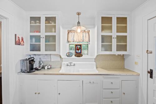 une cuisine avec des armoires blanches et un évier dans l'établissement Deannie's Cottage, à Fredericksburg
