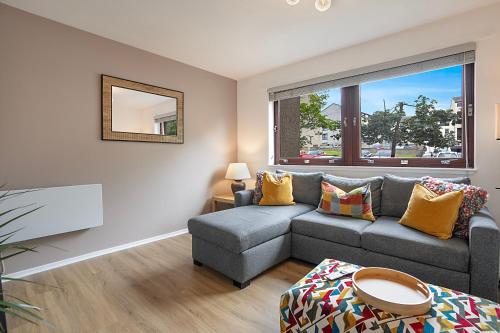 a living room with a gray couch and a window at Urquhart Terrace Lodge - Grampian Lettings in Aberdeen