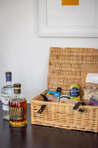 a basket of food and a bottle of whiskey on a table at Little Pitnacree in Pitlochry