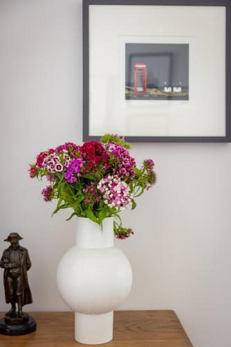 a white vase with flowers in it on a table at Little Pitnacree in Pitlochry