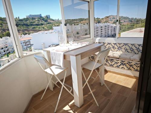 Una mesa y sillas blancas en una habitación con ventanas. en Charmoso T1 Varandas de Malpique, en Albufeira