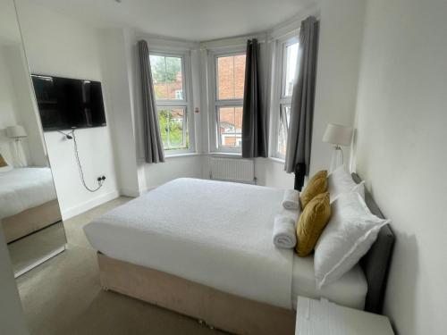a white bedroom with a bed and two windows at Stone Lodge 2 min Walk From Edgware Underground in Edgware