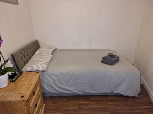a bed in a small room with a wooden table at Mile End Suites in London