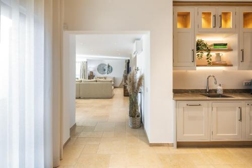 una cocina con armarios blancos y un jarrón de flores en Villa Avalon - Bedzy Luxury, en Almancil
