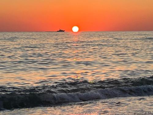 a sunset over the ocean with a boat in the water at OK Sakhli VIP in Shekvetili