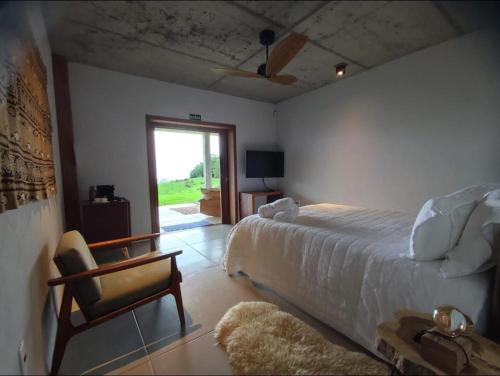 a bedroom with a bed and a chair and a window at VisttaSC in Praia Grande