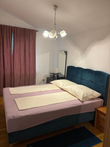 a bed with a blue headboard in a bedroom at Apartments Kristic in Lovran