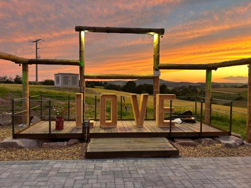 a wooden platform with a sunset in the background at AlmOtel - Auf der HerziAlm 