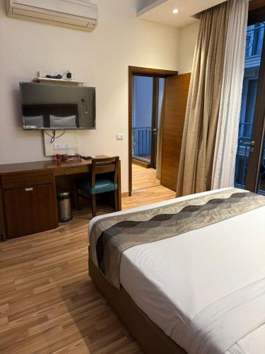 a hotel room with a bed and a desk and a tv at UDS Villa - Next to VFS, Walking to Connaught Place in New Delhi