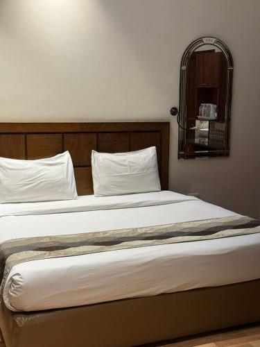 a bed with white sheets and a wooden headboard at UDS Villa - Next to VFS, Walking to Connaught Place in New Delhi