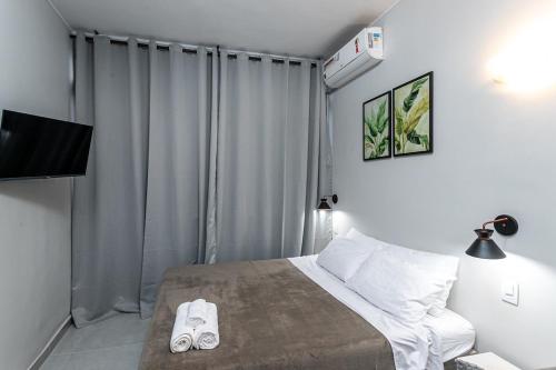 a bedroom with a bed with white sheets and a television at Studio Completo: Metrô e Aterro do Flamengo in Rio de Janeiro