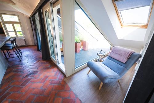 a room with a blue chair and a large window at Pension Merano in Jetřichovice