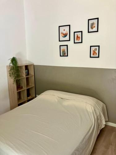 - un lit dans une chambre avec 4 photos sur le mur dans l'établissement Studio écusson Nîmois et cour ensoleillée, à Nîmes
