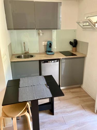 une petite cuisine avec une table et un évier dans l'établissement Studio écusson Nîmois et cour ensoleillée, à Nîmes