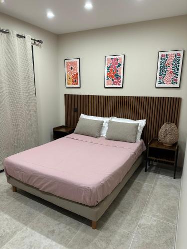 - une chambre avec un grand lit et des draps roses dans l'établissement les pins, à Chambonas