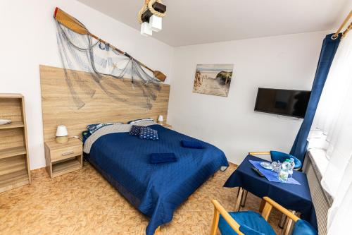 a bedroom with a blue bed and a tv at Dom Wypoczynkowy Anna - opcjonalnie śniadania w Starej Piekarni in Kołobrzeg