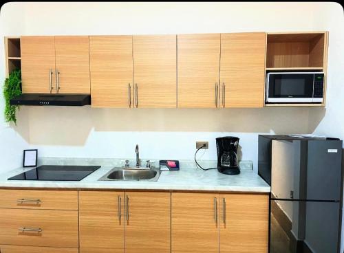 a kitchen with a sink and a microwave at Departamento a metros del Estadio BBVA, con acceso a terraza espectacular y asador in Monterrey