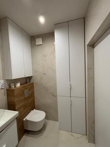 a bathroom with white cabinets and a toilet at Apartament w Twoim Stylu in Zamość