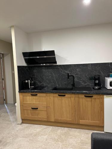 - une cuisine avec un plan de travail noir et un évier dans l'établissement les pins, à Chambonas