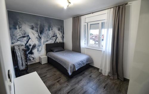 a small bedroom with a bed and a window at Apartman Kristina in Lovran