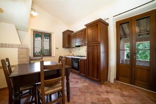 a kitchen with wooden cabinets and a table with chairs at Scappo in Umbria, La dolce Godera in Lugnano in Teverina