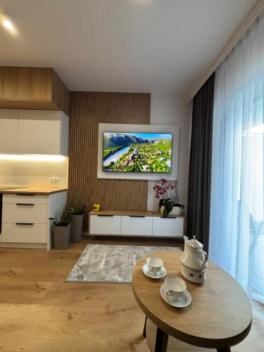 a living room with a table and a tv on the wall at Apartament w Twoim Stylu in Zamość