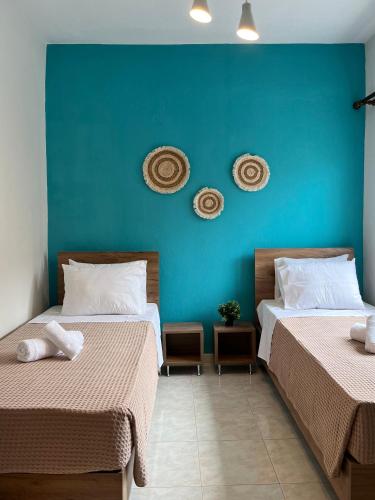 two beds in a room with a blue wall at Tilemaxos Apartment in Ierissos