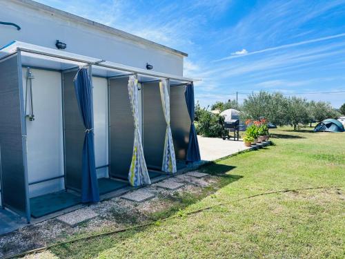 a house with blue and white curtains and a yard at CAMPING LASTE in Smoković