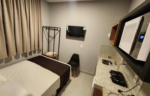 a hotel room with a bed and a desk and a television at FLATS CERRADO santa casa in Montes Claros