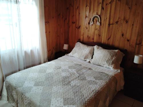a bedroom with a bed with a wooden wall at Las Cruces Cabaña de descanso in Las Cruces