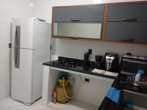 a kitchen with a white refrigerator and a stove at Kitnet temporada in Cabo Frio