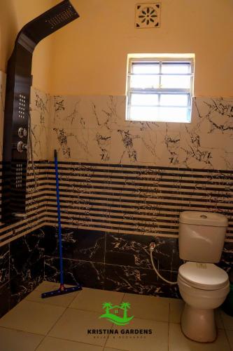 a bathroom with a toilet and black and white tiles at Kristina Gardens in Voi