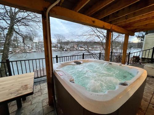 a jacuzzi tub on a deck with a view of the water at Cozy Cabin On the Lake with HotTub in Hopatcong