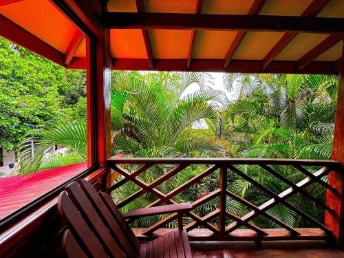 a balcony with two chairs and a view of palm trees at Casa Iguana in Puerto Viejo